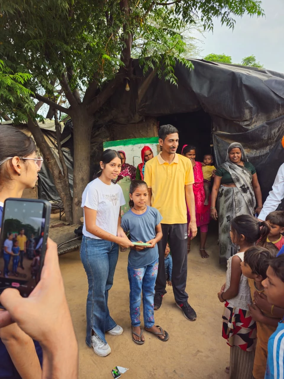 A volunteer handing a small gift to a girl during a settlement visit