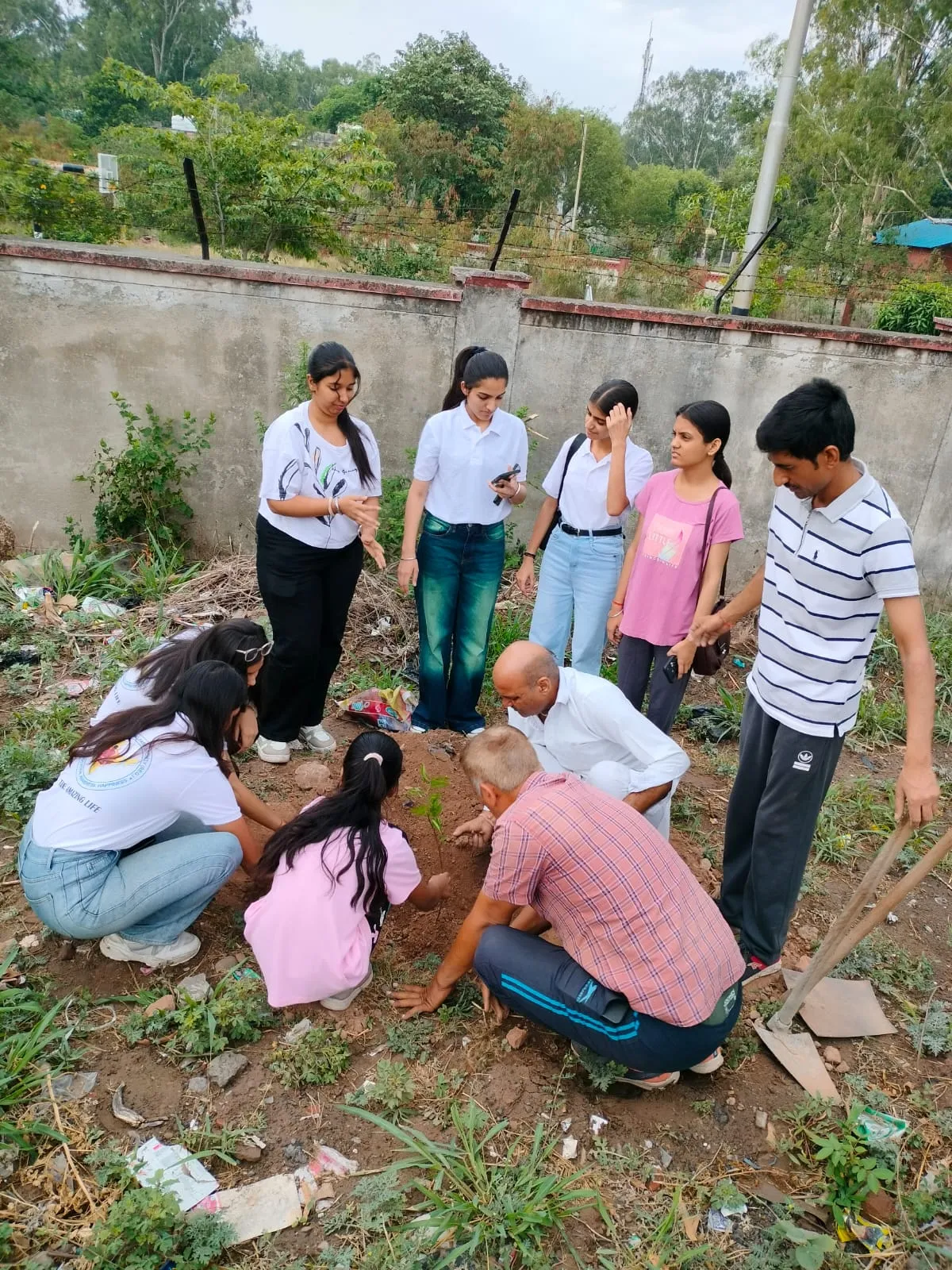 Volunteers in Society T-shirts planting a sapling together